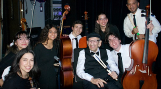 A photo of Saul Dreier posing with members of Scheck Hillel's orchestra